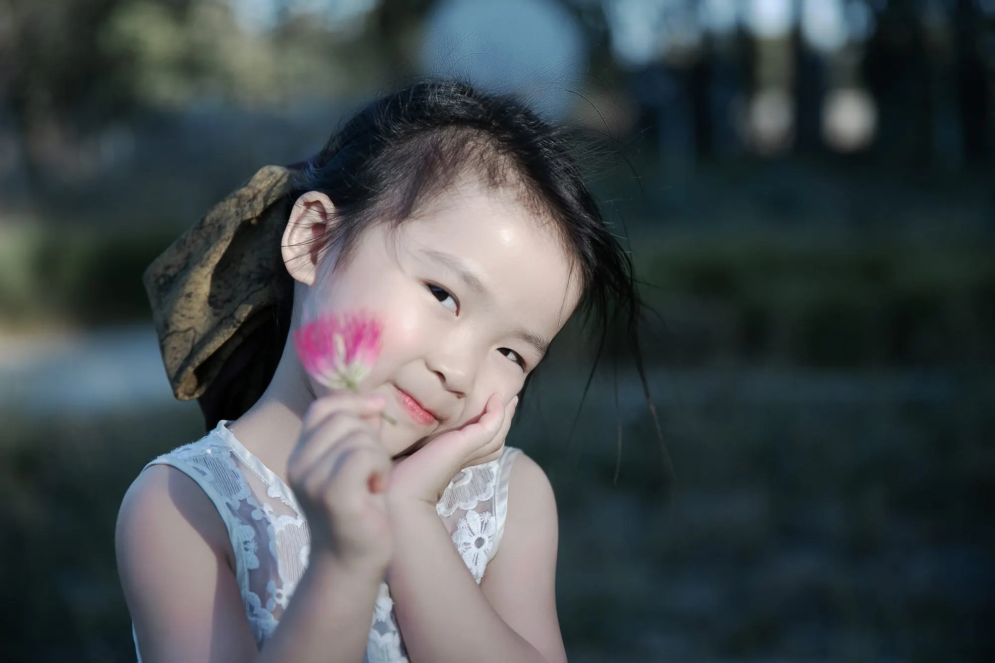 Little girl holding a pink blossom at golden hour, frame 6 of 10