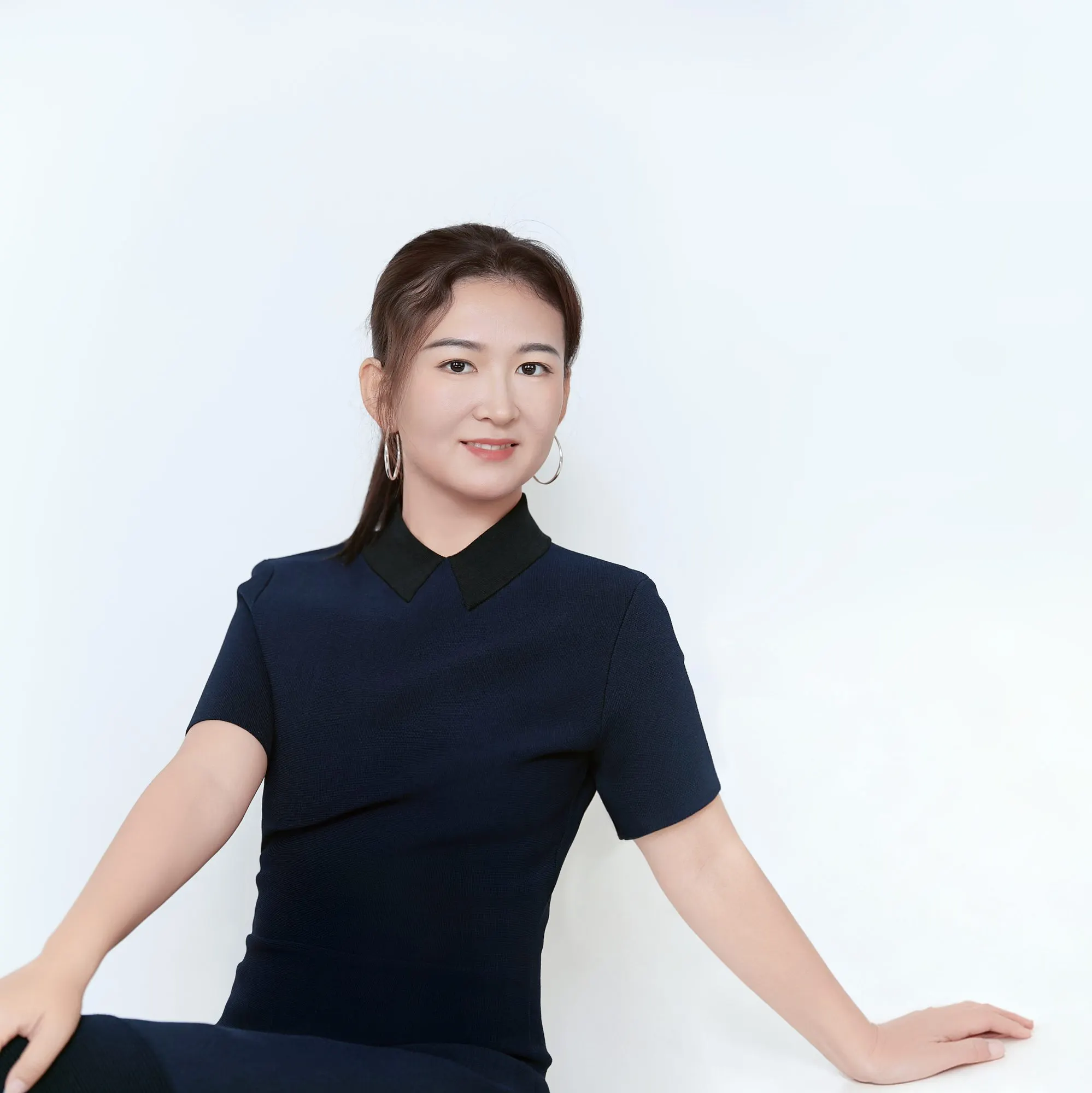 Studio headshot in a navy dress, frame 5 of 9