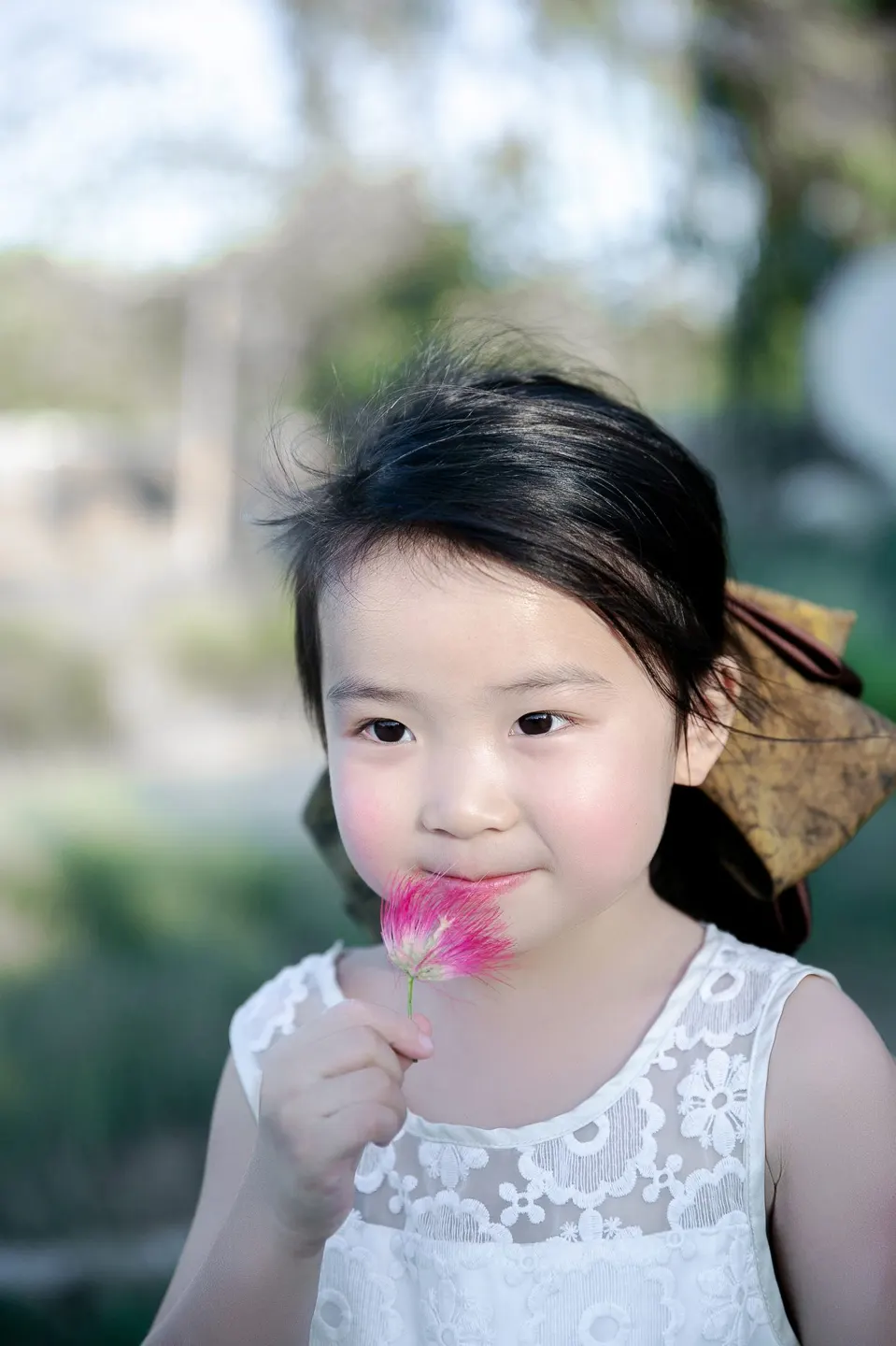 Little girl holding a pink blossom at golden hour, frame 7 of 10