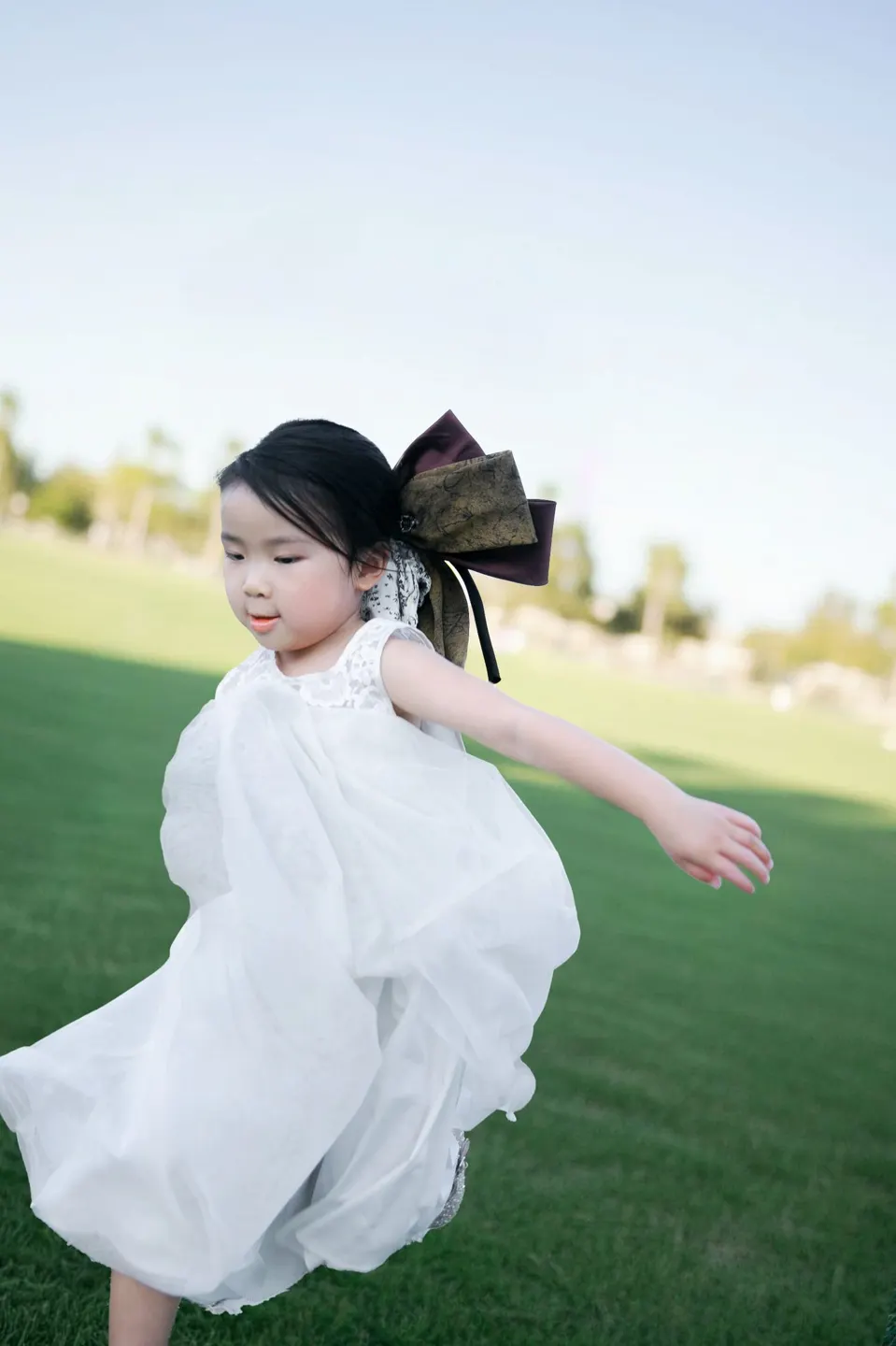 Little girl holding a pink blossom at golden hour, frame 9 of 10