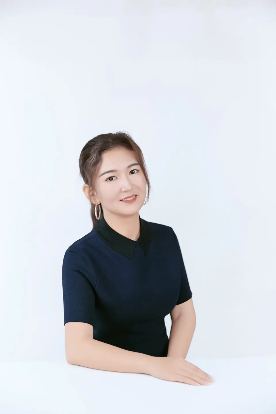 Studio headshot in a navy dress, frame 4 of 9