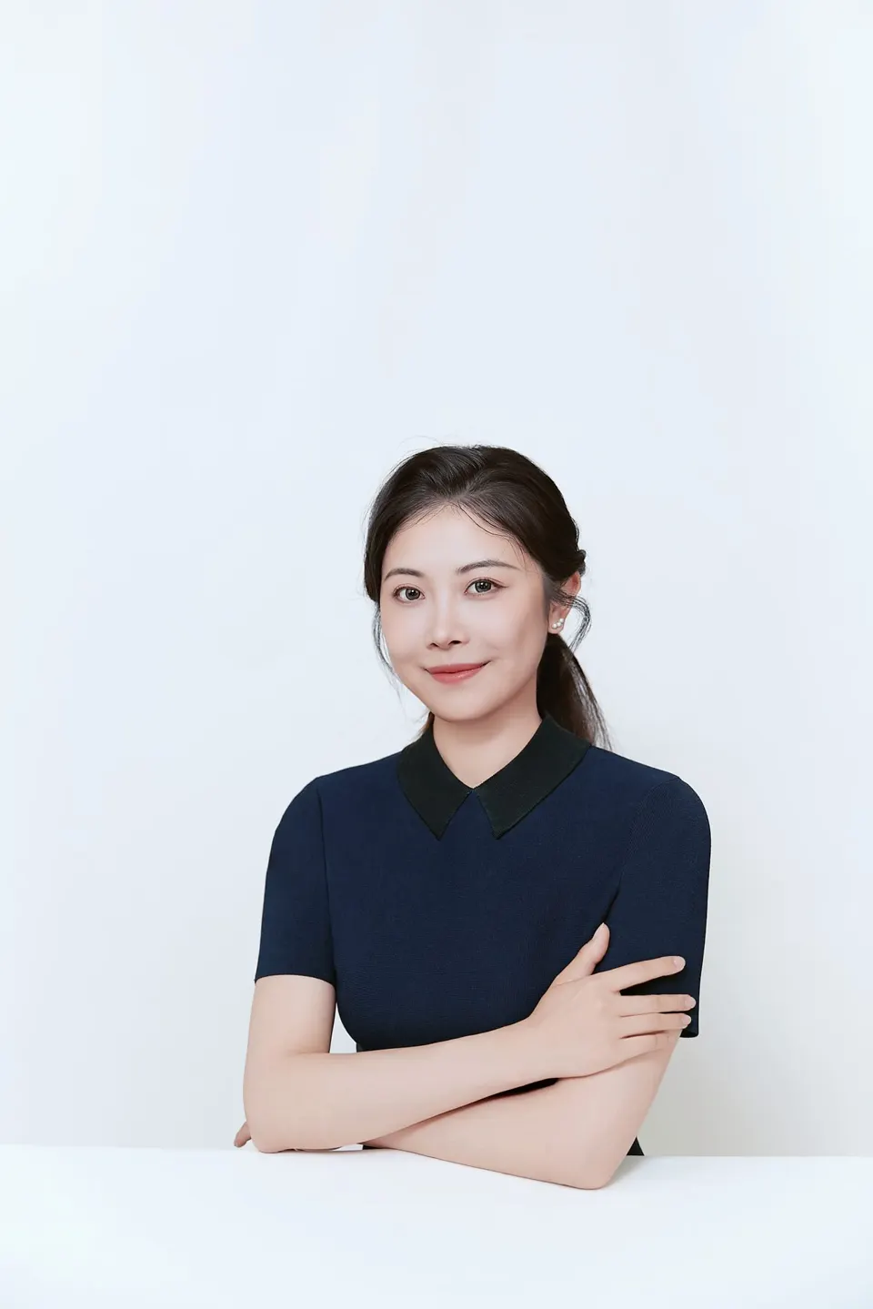 Studio headshot in a navy dress, frame 9 of 9