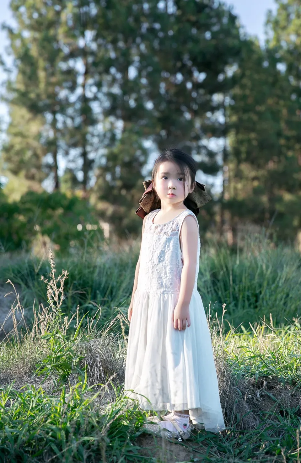 Little girl holding a pink blossom at golden hour, frame 2 of 10