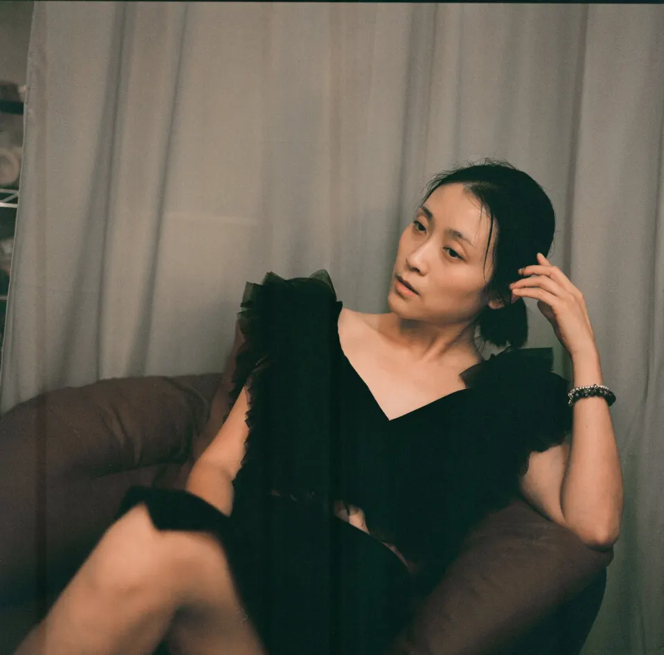 Jianing, seated in a black ruffled dress